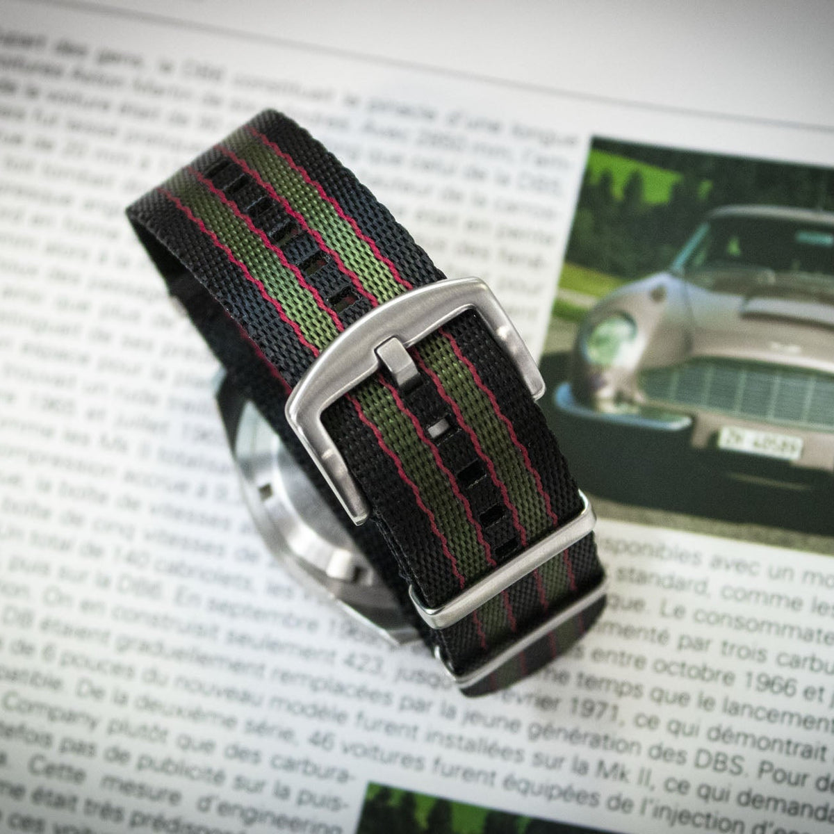 Watch strap with green and red pattern on a magazine page with Aston Martin image