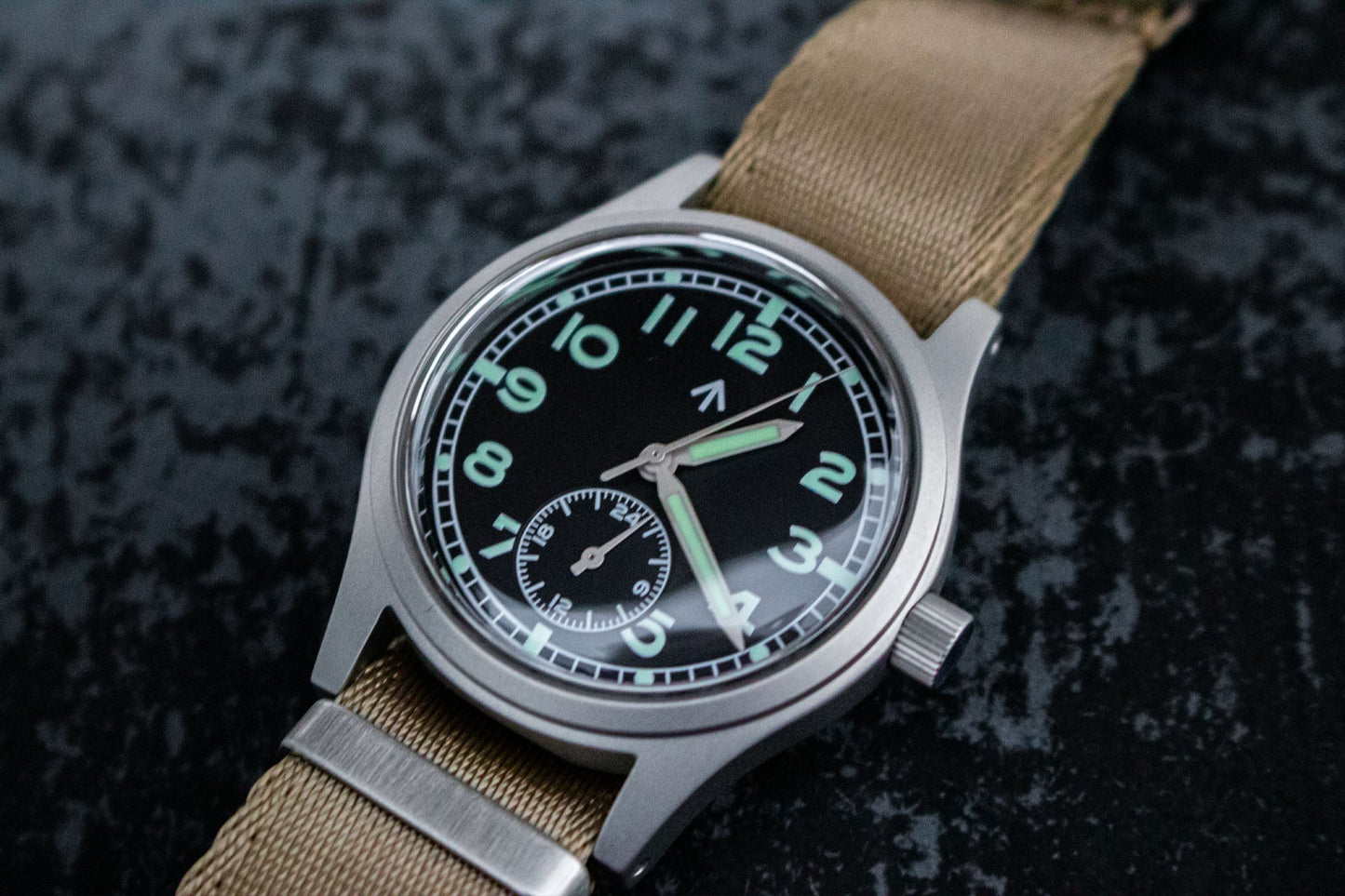 Close-up of the black dial of the Aeschbach x Enoksen 'Fly' E03/H watch, highlighting the white markers, Super-Luminova, and 24-hour hand.