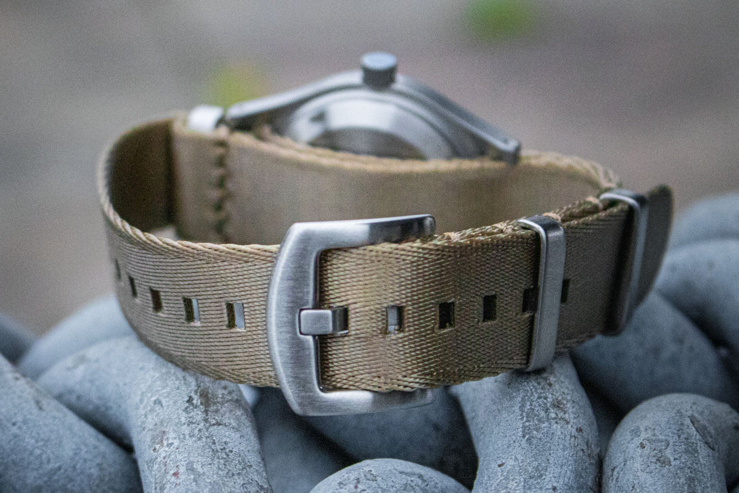 The Aeschbach x Enoksen 'Fly' E03/H watch displayed with a khaki seatbelt NATO strap.