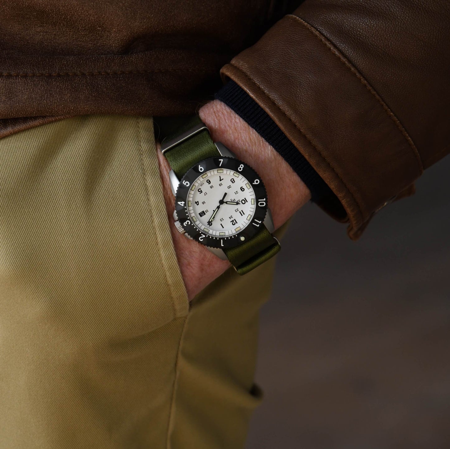 Close up of wrist on male model wearing the By Enoksen Tactic E09A watch on a green Nato strap.