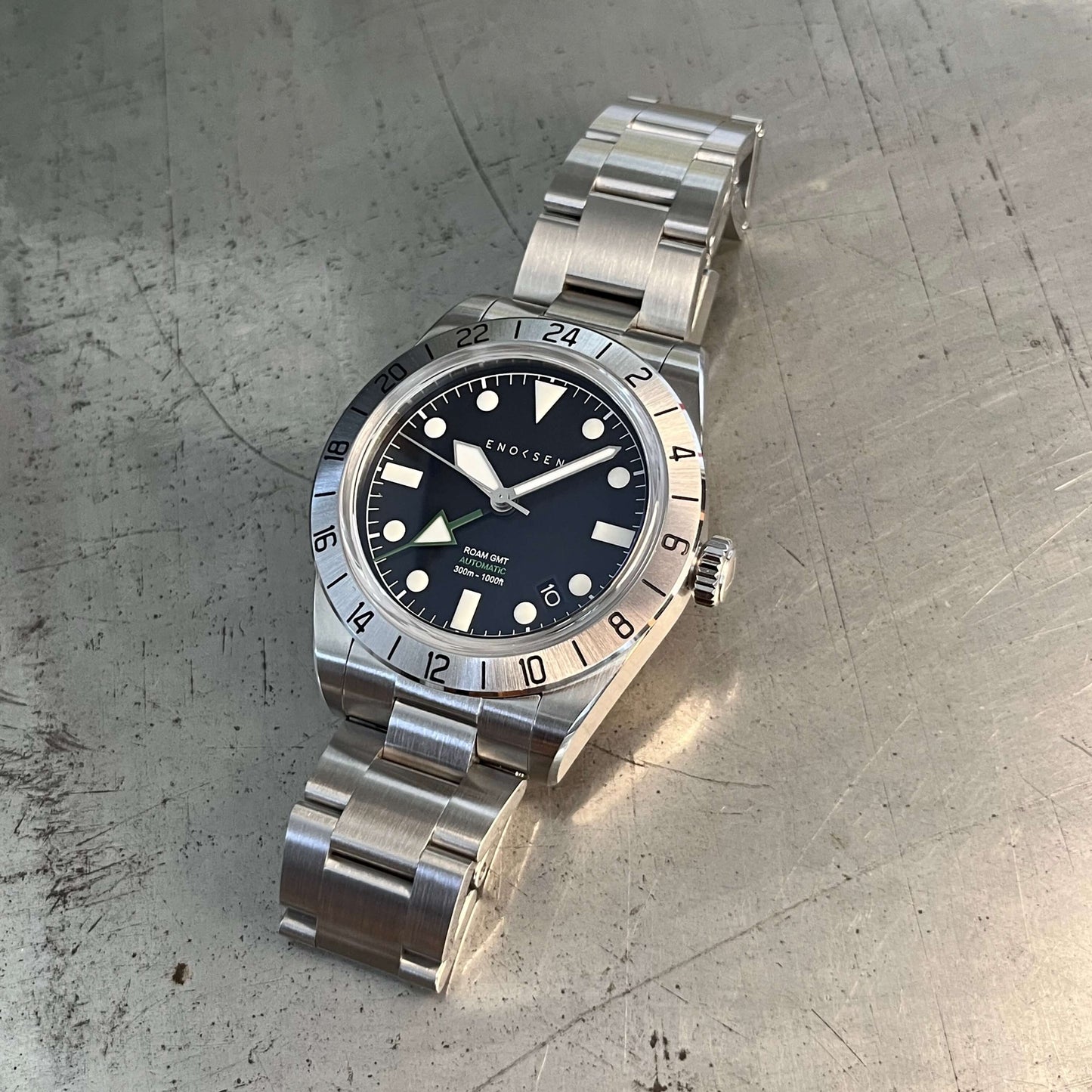 GMT watch, close-up. Emphasizes the quality of the watch and clearly shows the green GMT hand set against the black dial, providing a classic appearance.