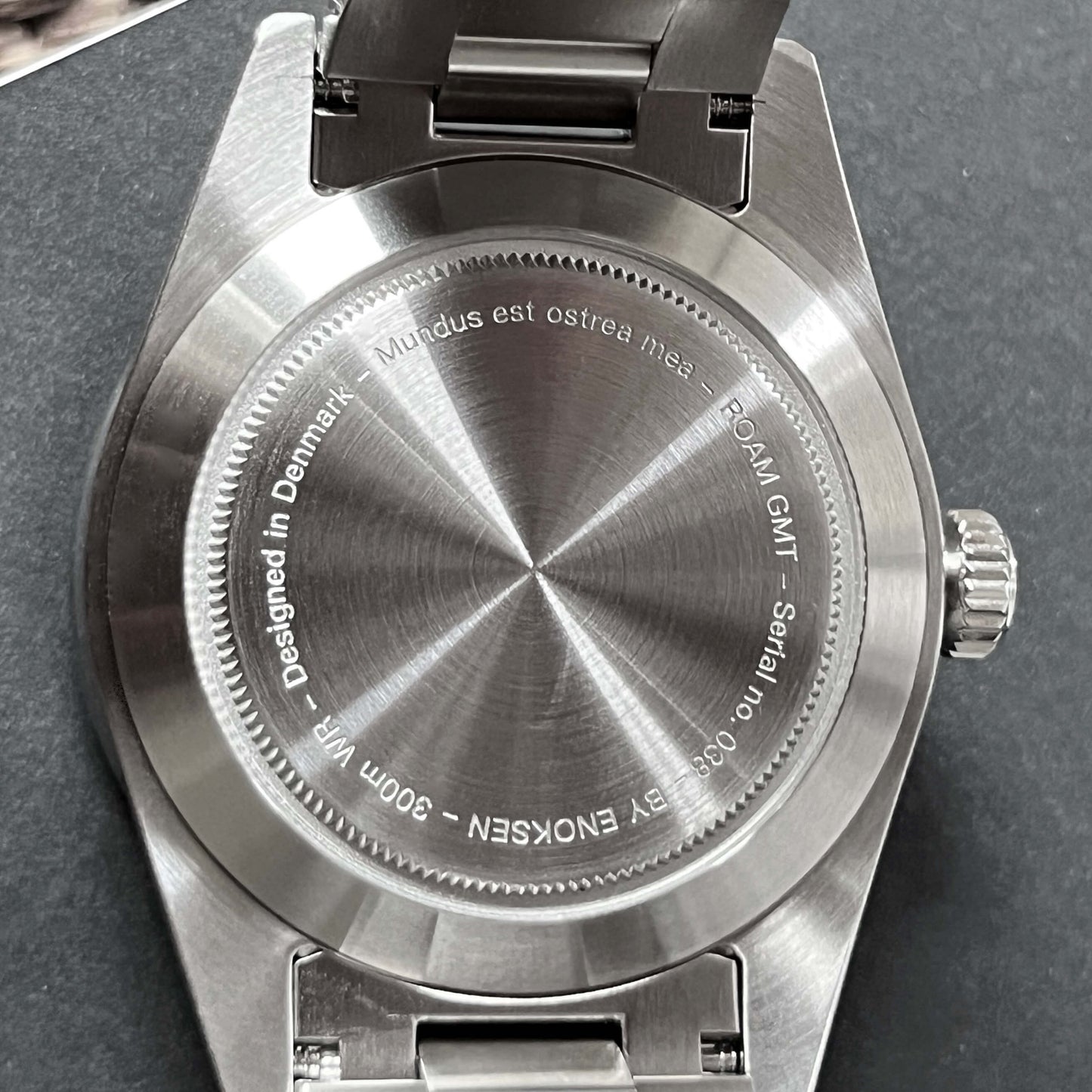 Back plate on GMT featuring engraving: Designed in Denmark, ROAM GMT, By ENOKSEN, Mundus est ostrea mea, alongside a unique serial number of the watch.