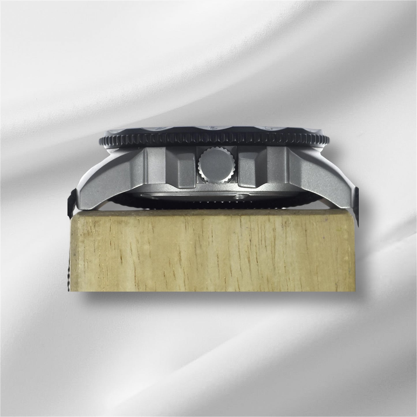 A side-on view showcasing the polished steel case of By Enoksen Tactical watch. The image emphasizes the watch's study build crown and black rotating bezel.
