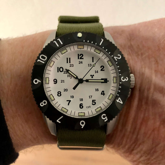 A close up view of the By Enoksen tactical E09A worn with a green Nato strap. The image captures the watch's rugged yet refined design.