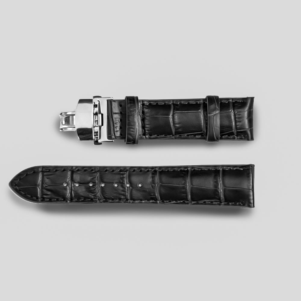 Black crocodile-patterned watch strap with silver buckle on a light gray background