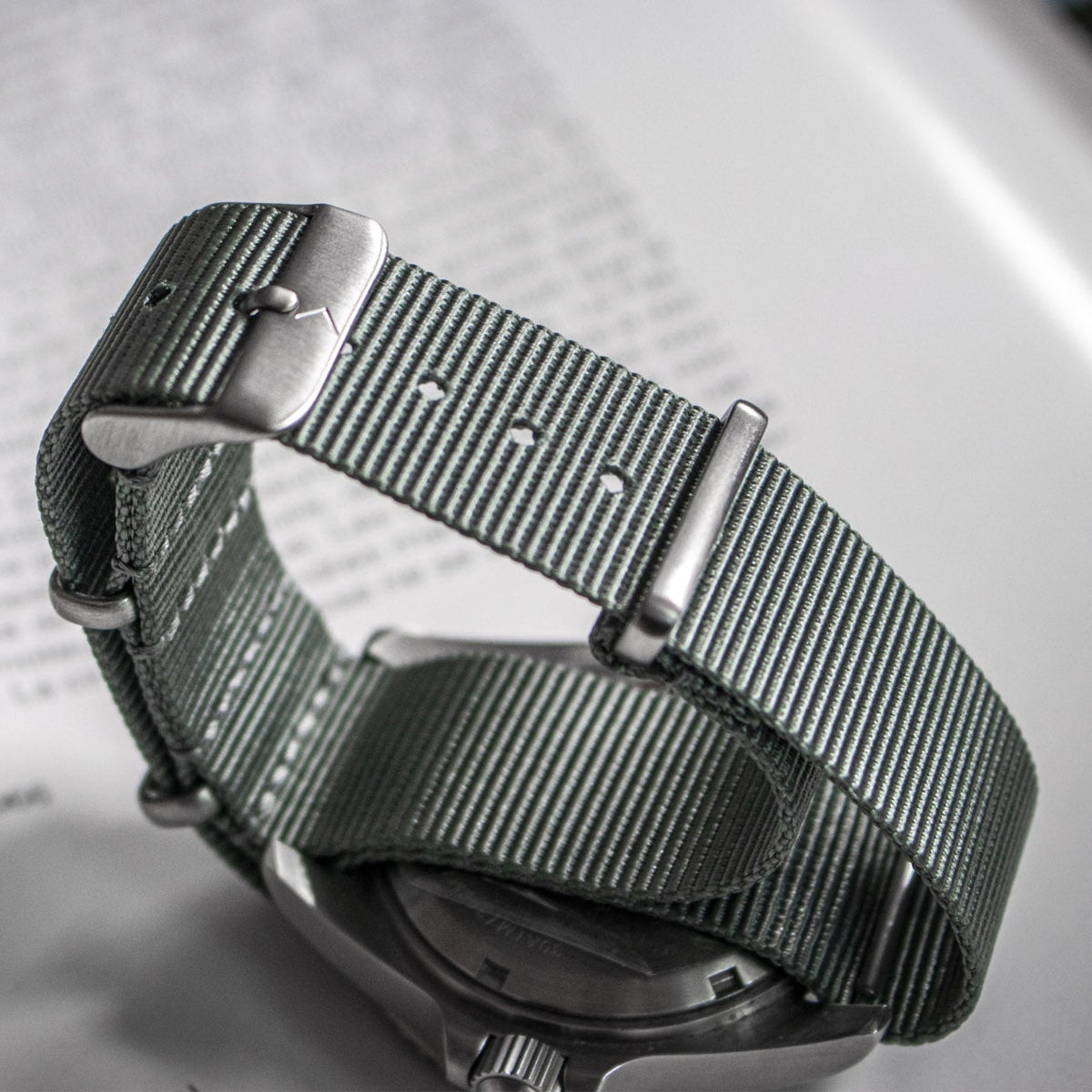 Silver watch with a textured strap on a blurred background