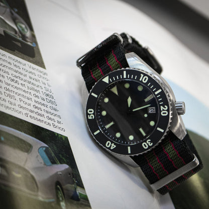Black wristwatch with a red and green strap on a magazine page