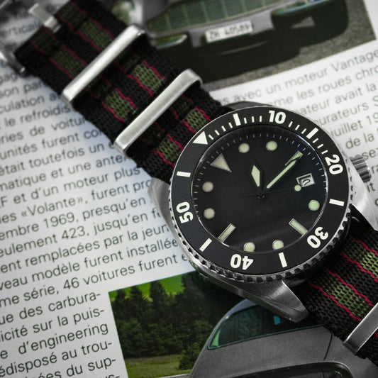 Watch with a black dial and NATO strap on a magazine page