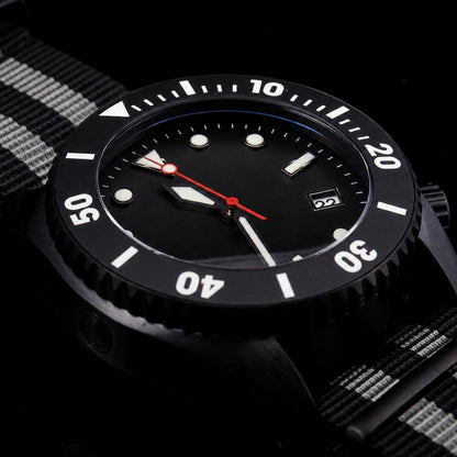 A close-up of a black wristwatch with a black dial, white bezel numerals, and a red second hand, paired with a black and white striped fabric strap, set against a dark background.