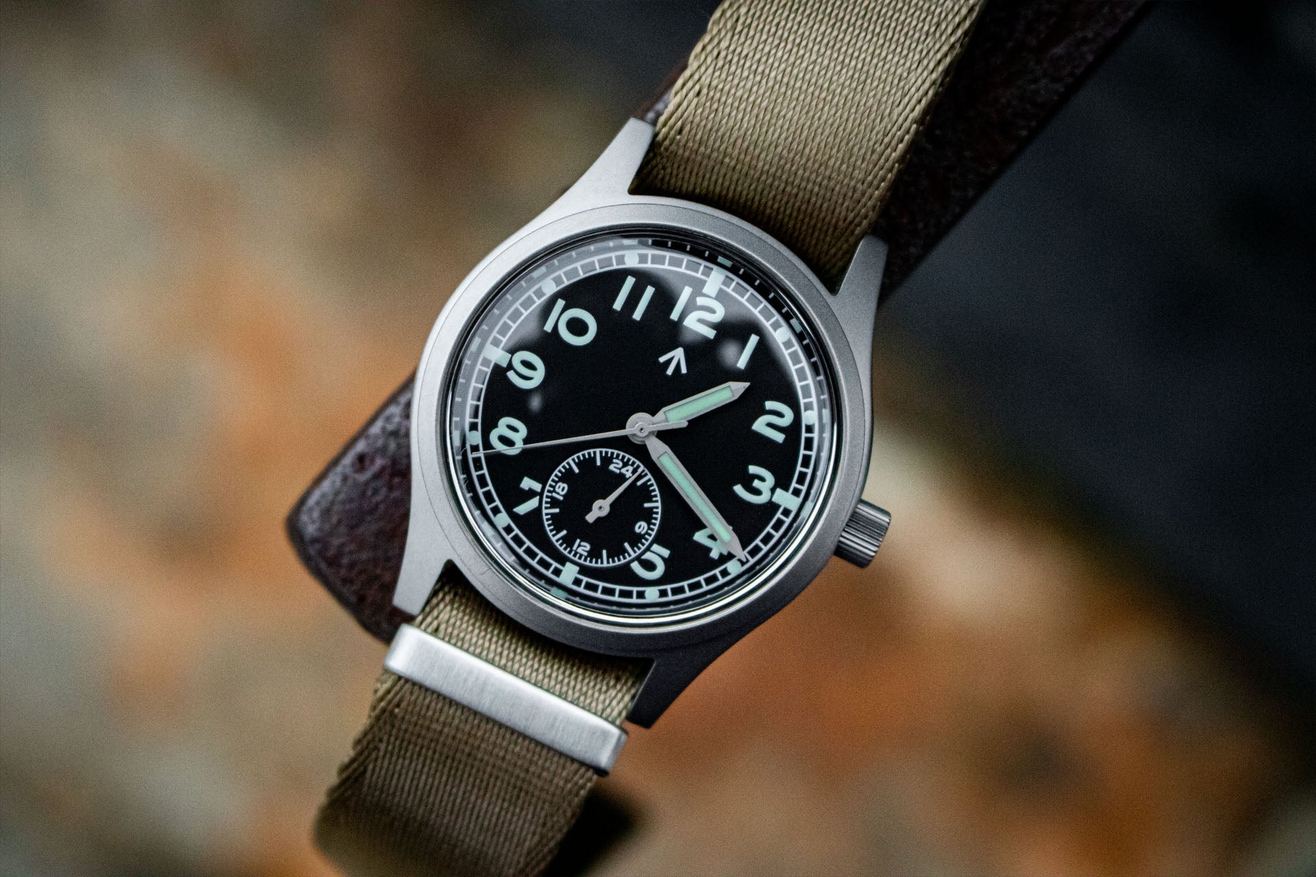 Close-up of the black dial of the Aeschbach x Enoksen 'Fly' E03/H watch, highlighting the white markers, Super-Luminova, and 24-hour hand.