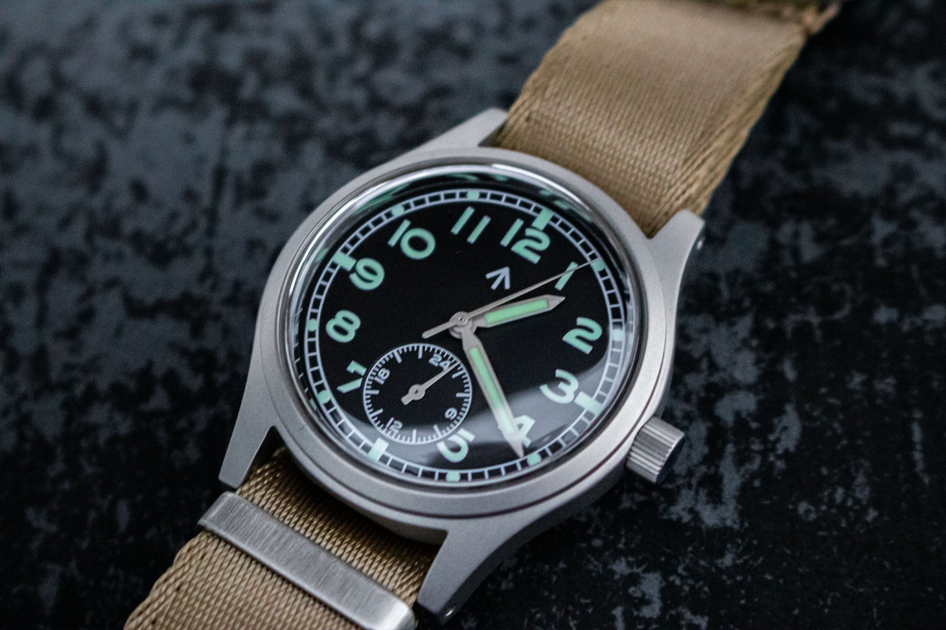 Close-up of the black dial of the Aeschbach x Enoksen 'Fly' E03/H watch, highlighting the white markers, Super-Luminova, and 24-hour hand.