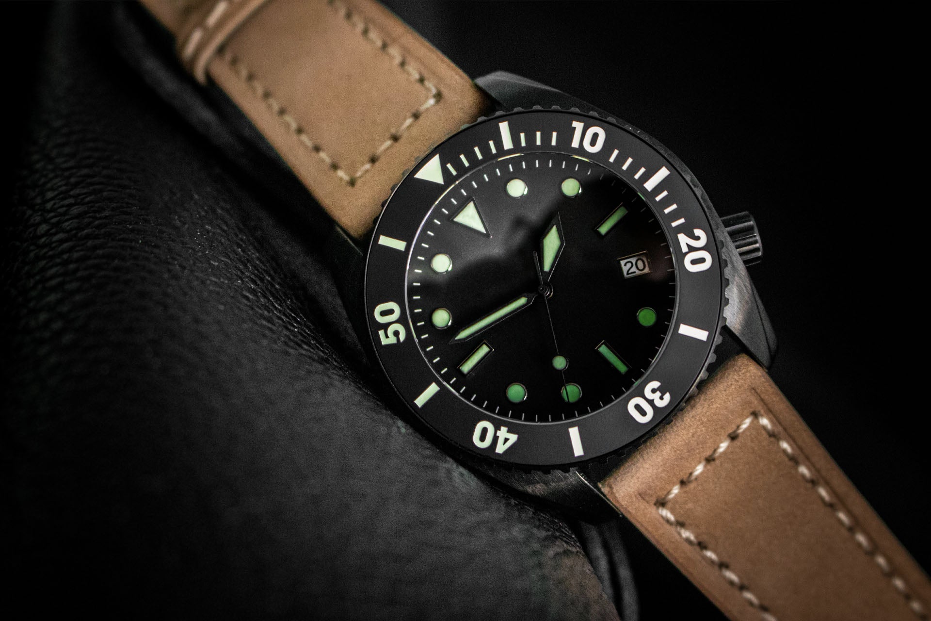 Watch with brown leather strap and black dial on a dark background