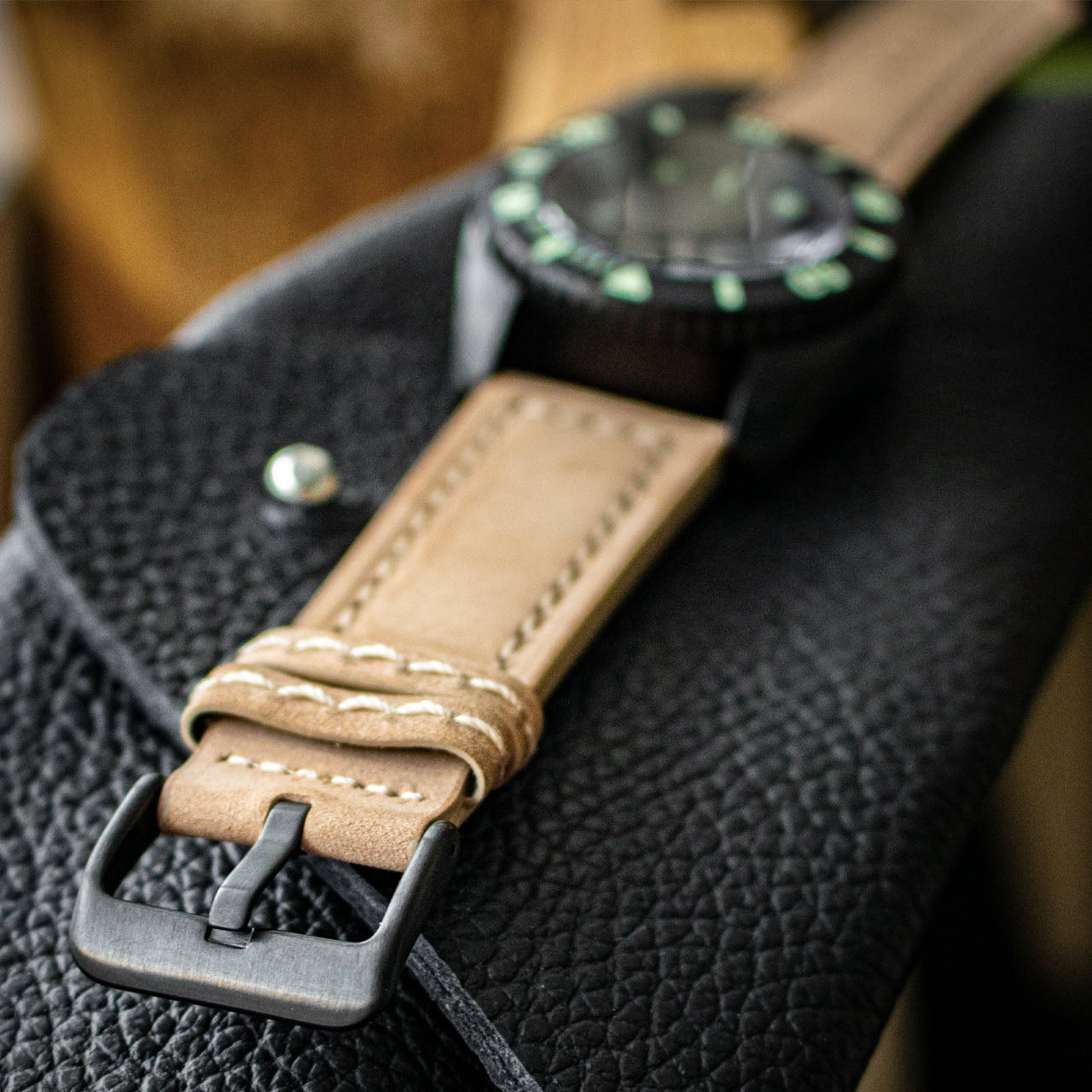 Watch with a brown leather strap on a black textured surface