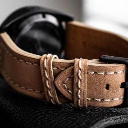 Brown leather watch strap on a textured surface with a blurred background