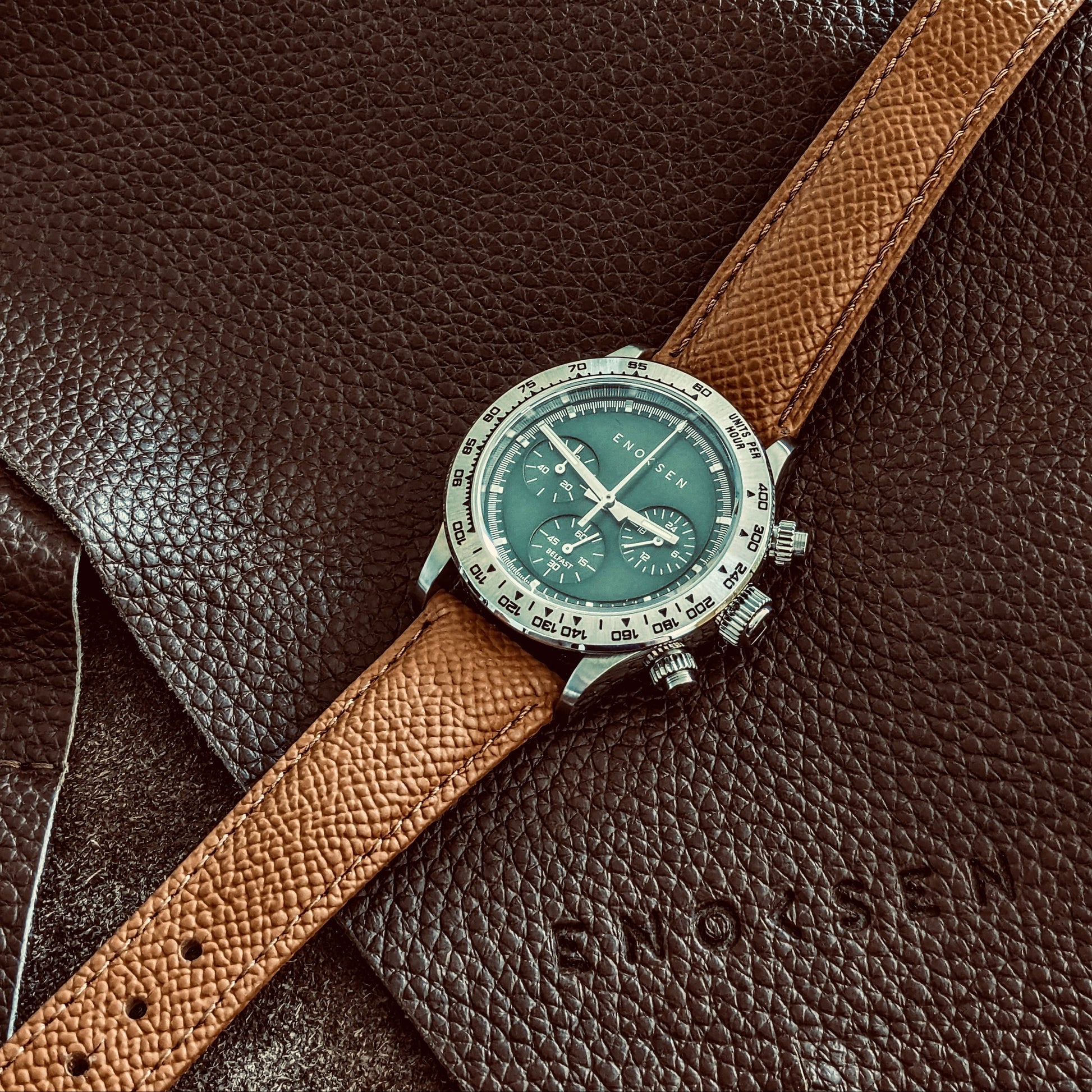 Watch with a brown strap on a brown leather surface