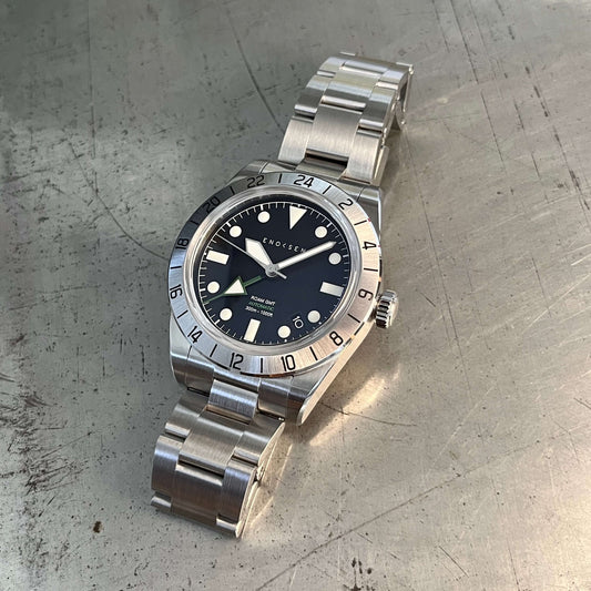 GMT watch, close-up. Emphasizes the quality of the watch and clearly shows the green GMT hand set against the black dial, providing a classic appearance.
