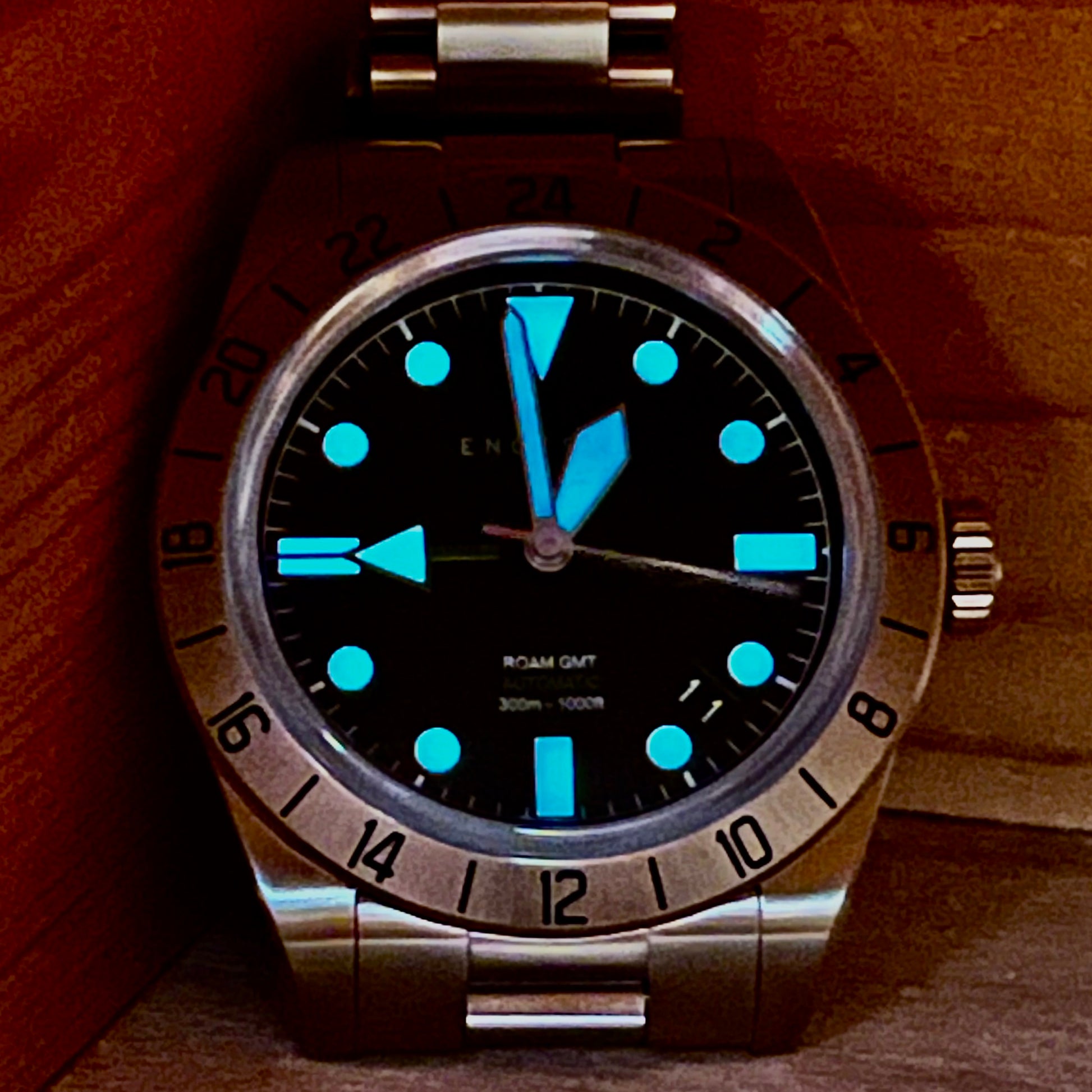 Front view of the watch in darkness showcasing the bright blue luminescent on the hands and minute markers, adding great visibility to the watch.