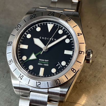 Close up of dial, showing the crisp hour, minute and seconds hands, as well as the Enoksen green 24-hour GMT hand and rotating bezel.