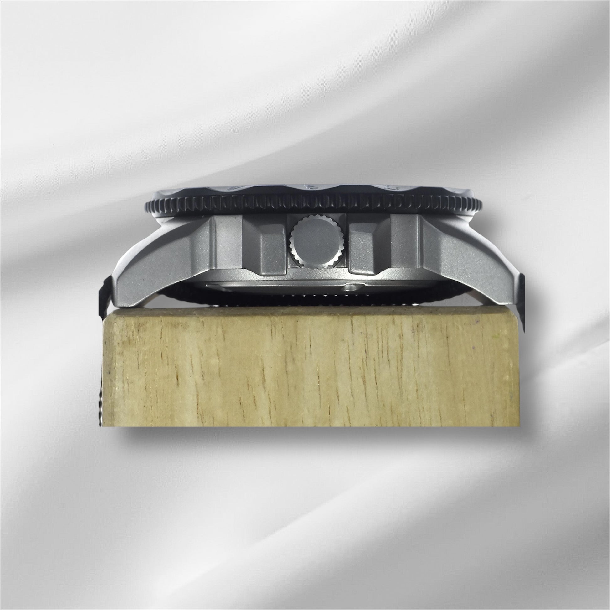 A side-on view showcasing the polished steel case of By Enoksen Tactical watch. The image emphasizes the watch's study build crown and black rotating bezel.