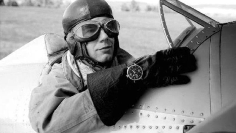 Black-and-white historical photograph of a wartime pilot wearing a large wristwatch, illustrating the aviation context behind the B-Uhr observer watch.