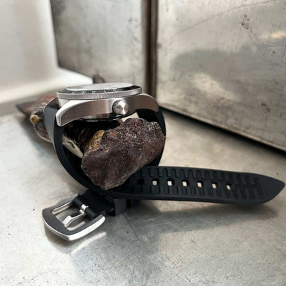 Side view highlighting the unidirectional 120-click bezel and 12-hour markers and black natural rubber strap with brushed steel buckle.