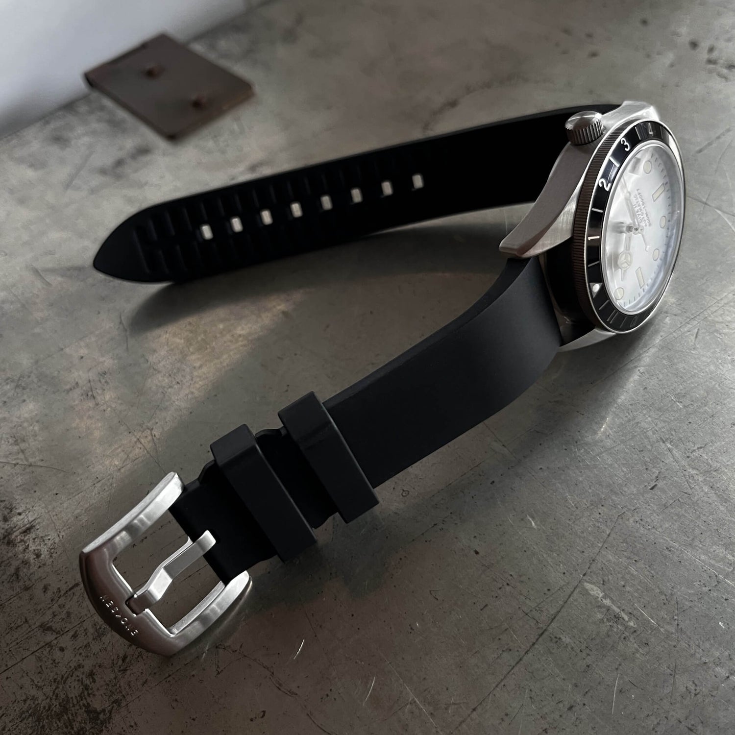 Black natural rubber strap with brushed steel buckle and Enoksen logo engraving.