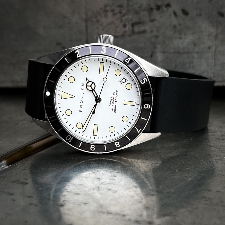 Enoksen Dive II E12/A Skin Diver 39mm with white dial on black rubber strap, front view. View on a metal surface with reflection.
