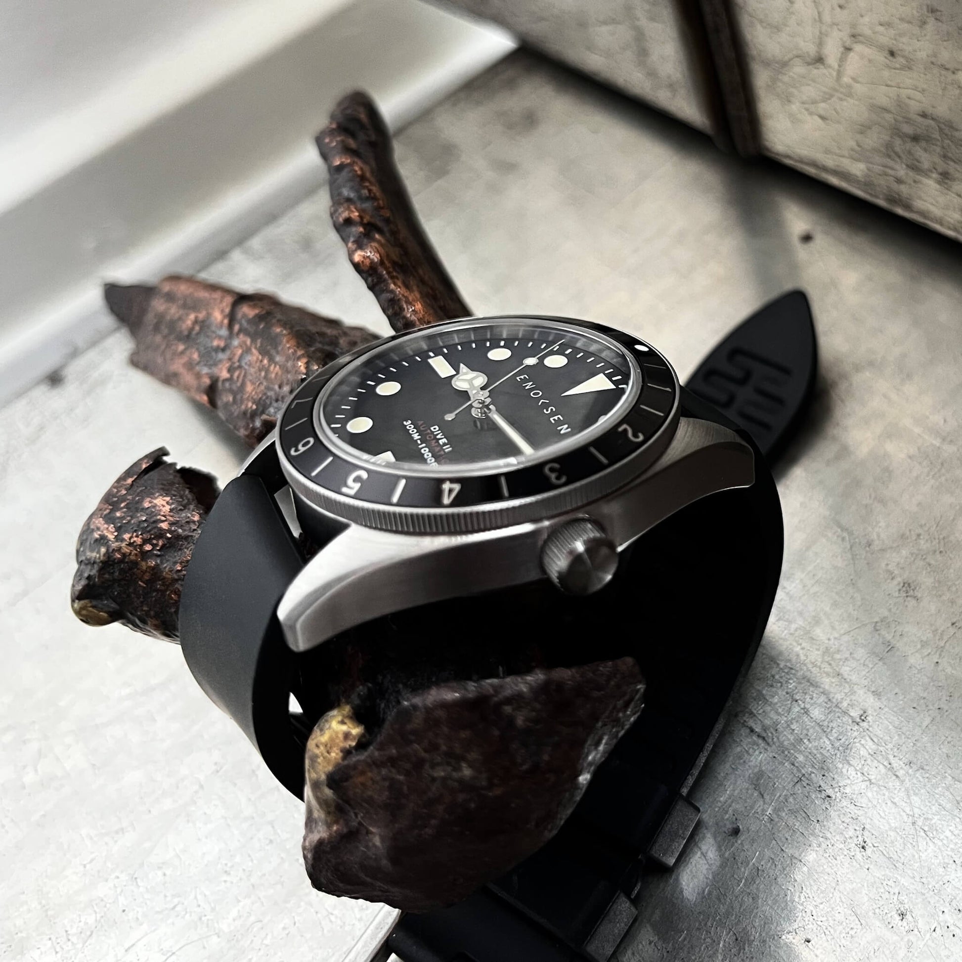 Dive II black dial on black rubber strap, angled view of the Dive II with black dial on black rubber strap, highlighting the domed sapphire crystal and 12-hour bezel.