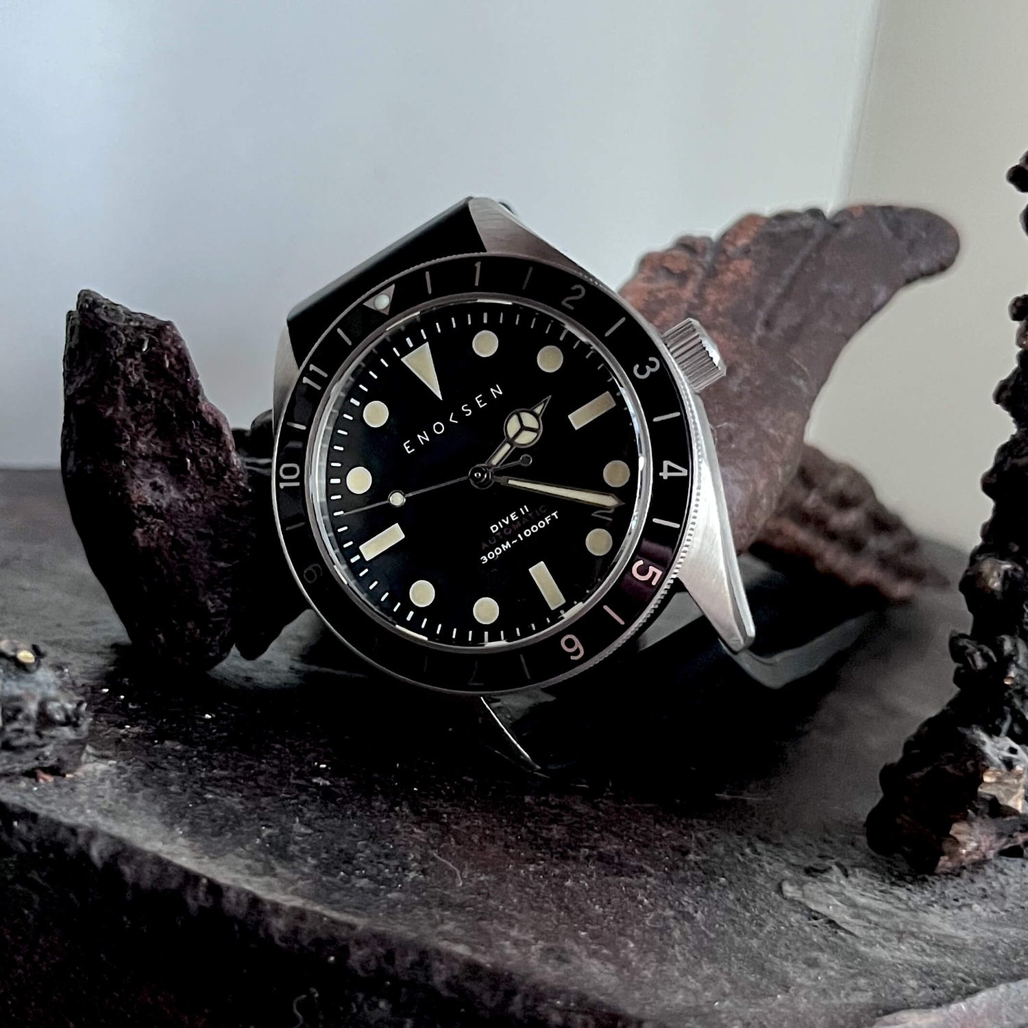 Dive II with black dial photographed with a bronze sculpture, showing the classic skin-diver silhouette.