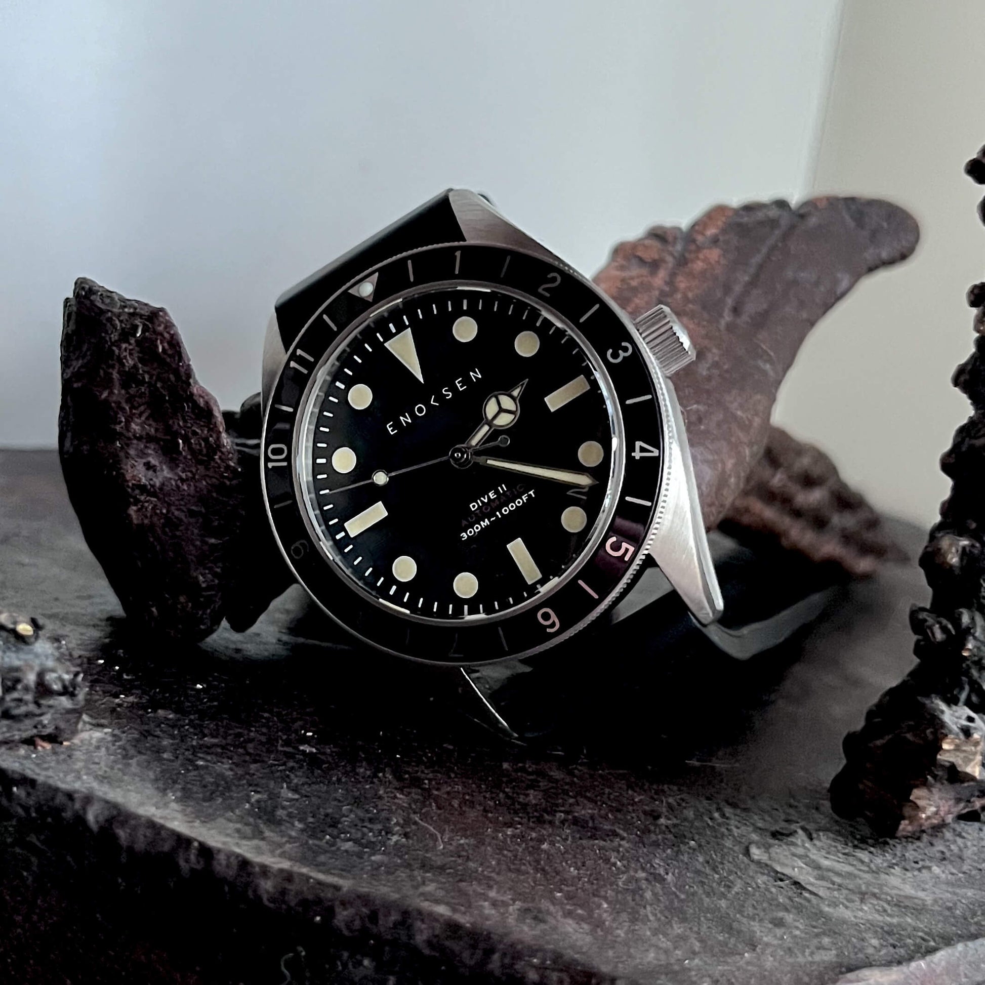Dive II with black dial photographed with a bronze sculpture, showing the classic skin-diver silhouette.