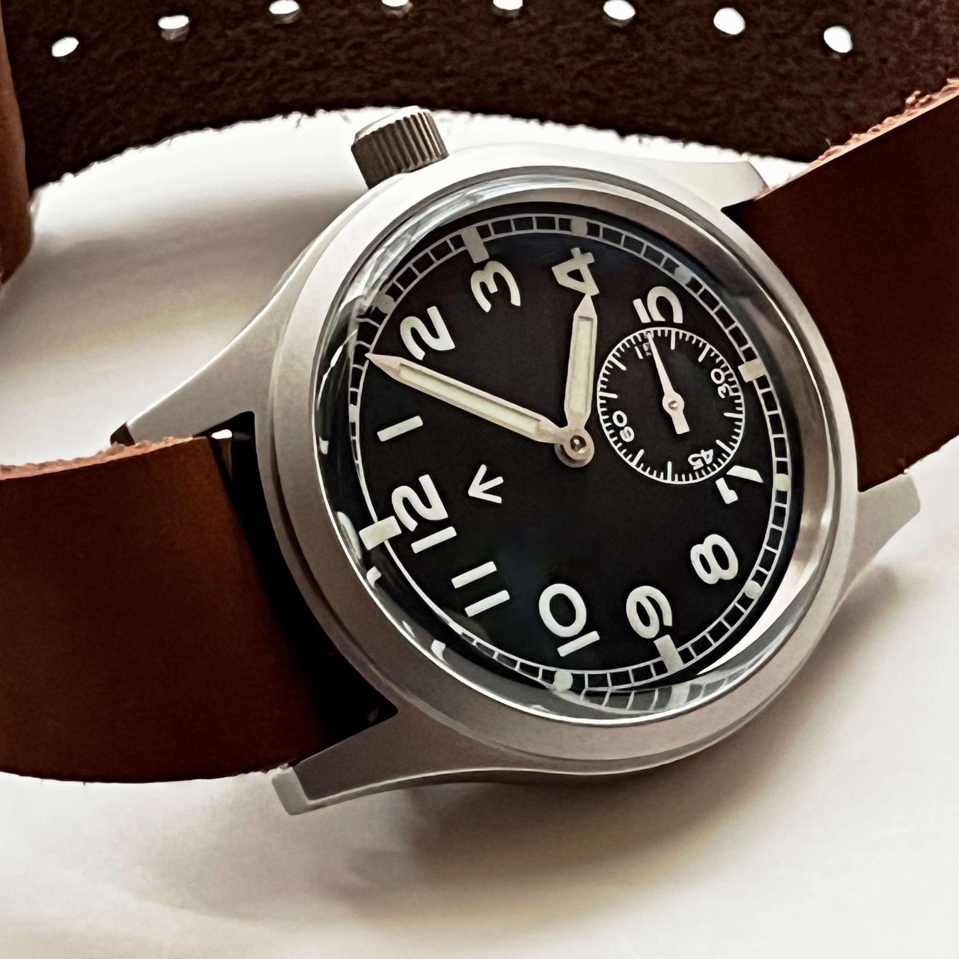 Dial close-up showing Arabic numerals and the railroad minute track on Enoksen Fly E03/M. Showcasing the Domed sapphire crystal. And how the iconic curved profile gives a classic look as well as a modern anti-reflective clarity and scratch resistance.