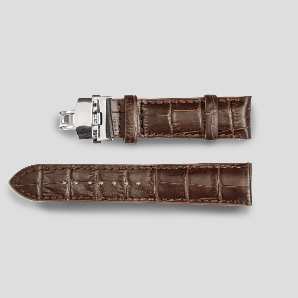 Brown crocodile-patterned watch strap with silver clasp on a light gray background