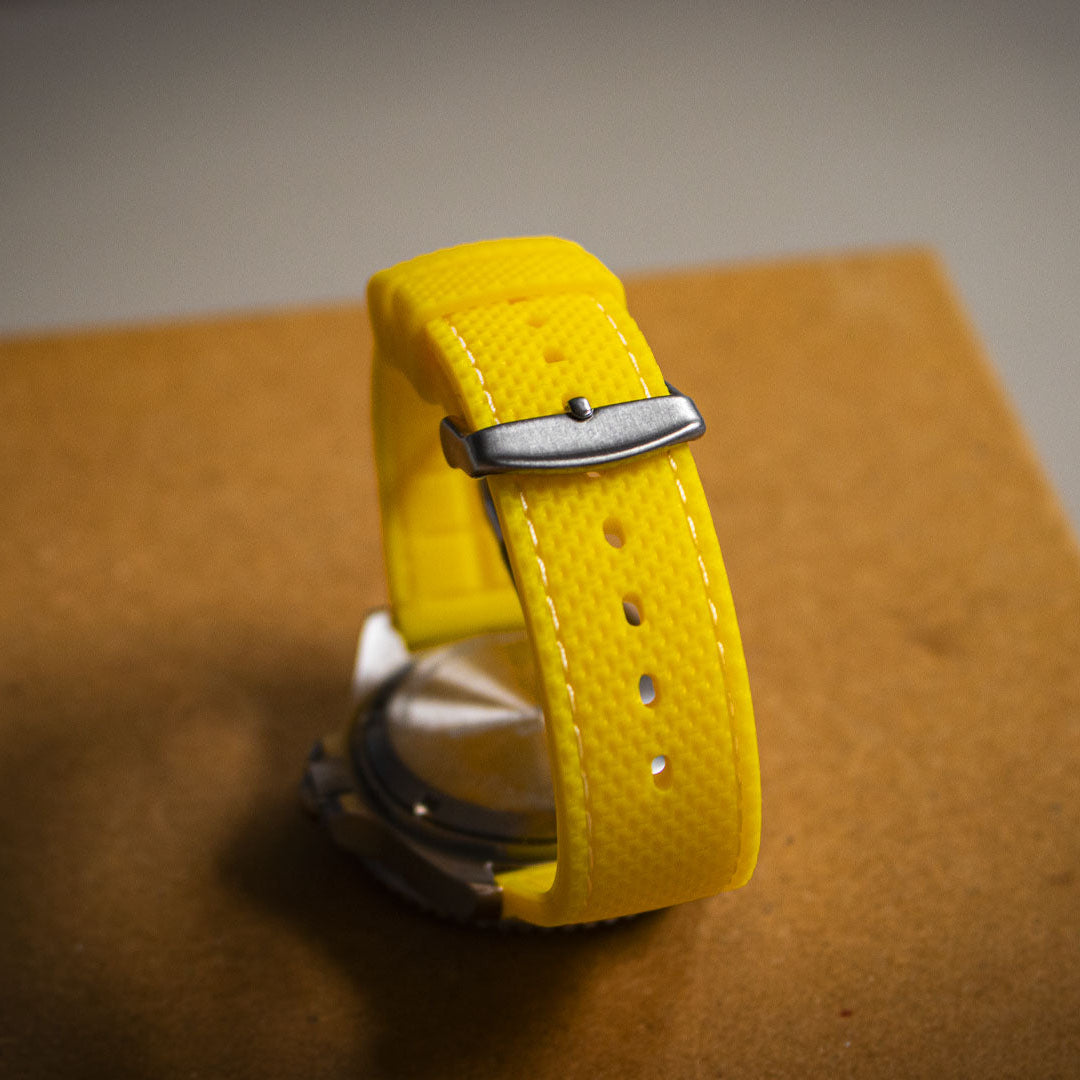 Yellow watch strap with silver buckle on a brown surface