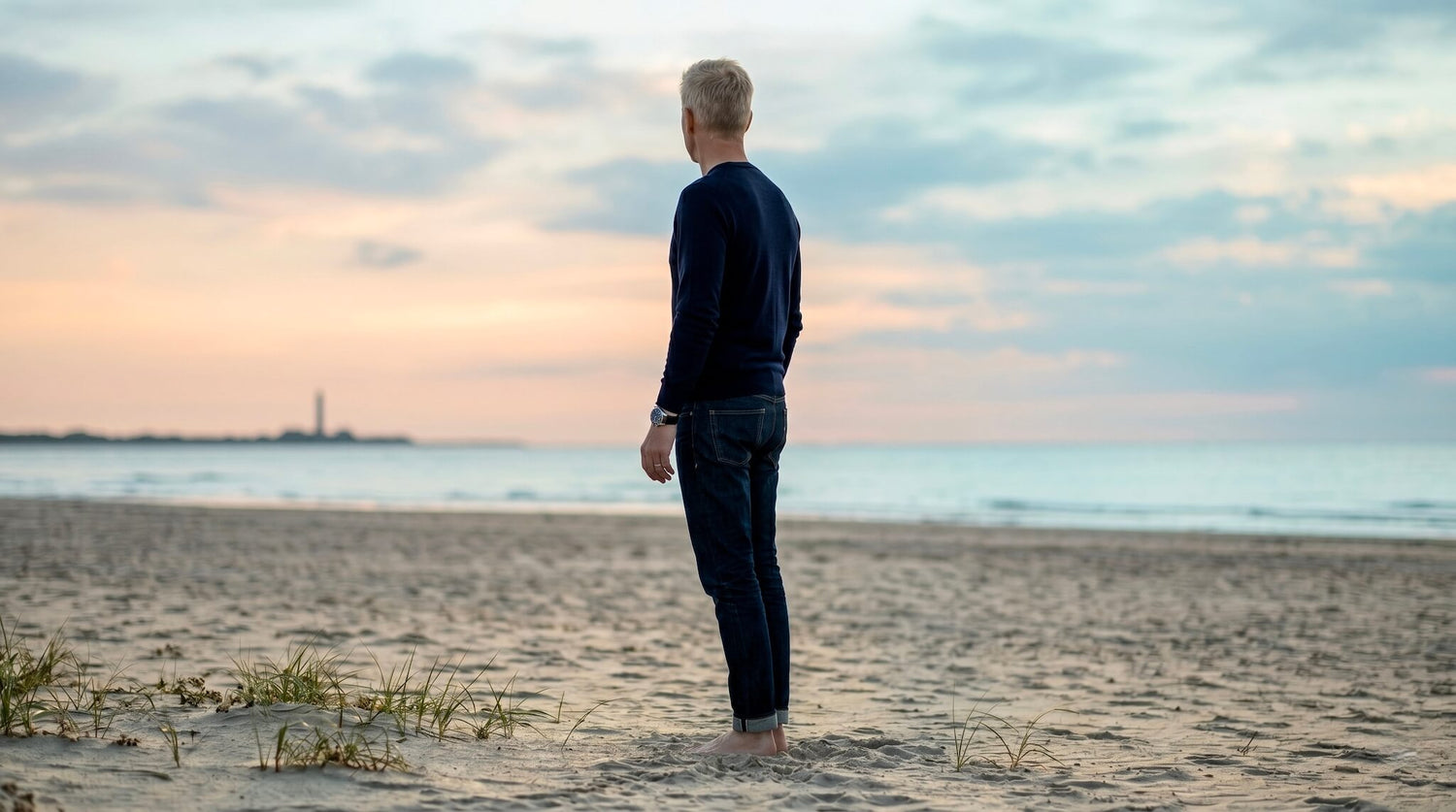 Man standing on a Danish beach at sunset wearing a watch.