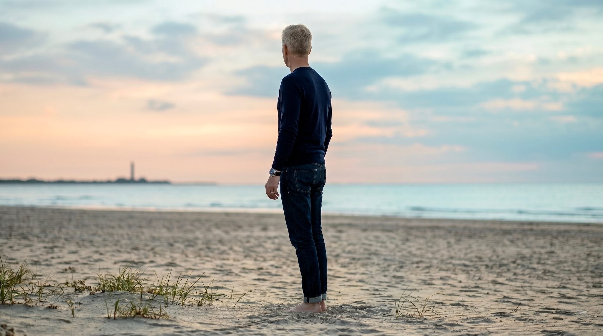Man standing on a Danish beach at sunset wearing a watch.
