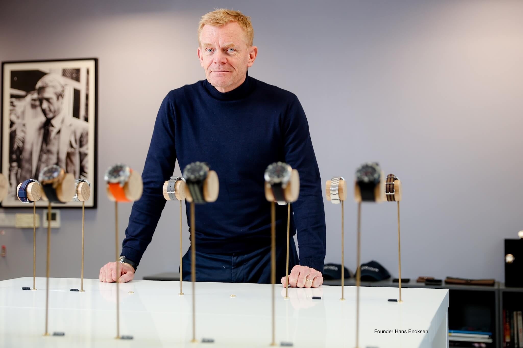 Founder Hans Enoksen in Enoksen Watches showroom. Watches displayed on wooden sticks in front of him.