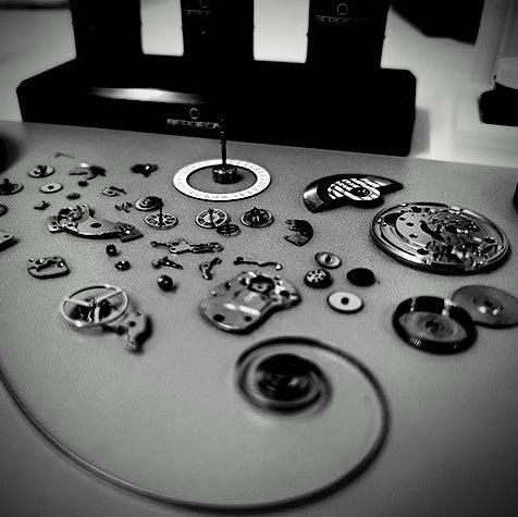 Collection of mechanical watch components on a flat surface